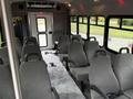 Interior of a 2014 Ford Econoline with gray seating arranged in rows and a doorway at the back