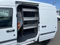A 2013 Ford Transit Connect with its side door open revealing metal shelving inside the cargo area