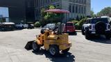 A yellow 2024 Traner TR45 with a cab and front loader attachment is parked on a paved surface