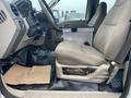 Interior view of a 2009 Ford F-450 SD showing the driver's seat and dashboard area with a metal box on the floor and a textured mat on the ground