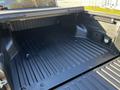 The image shows the bed of a 2021 Toyota Tacoma featuring a black spray-on liner and a flat surface with grooves for cargo stability