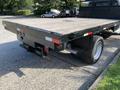 A 2013 Ford F-450 SD flatbed truck featuring a wooden flatbed and a black chassis with rear lights and a tow hitch