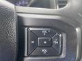 Close-up of the steering wheel controls of a 2017 Ford F-550 featuring buttons for volume and media control