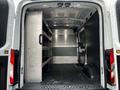 Interior view of a 2020 Ford Transit cargo van featuring storage shelves on one side and a spacious empty cargo area