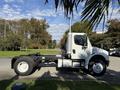 A 2003 Freightliner M2 106 truck in white with a visible chassis and cab, featuring a tall exhaust pipe on the driver's side