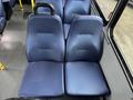 A pair of blue fabric bus seats with textured upholstery set in a vehicle interior