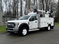 A white 2018 Ford F-550 utility truck equipped with a lift bucket and tool compartments on the sides