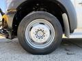 A close-up of the front wheel of a 2011 Ford F-550 showcasing a silver wheel rim with multiple bolt holes and a black tire