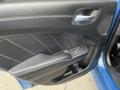 The interior door panel of a 2022 Dodge Charger featuring black upholstery with white stitching a door handle and a window control button