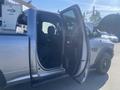A silver 2021 RAM 1500 pickup truck with an open door revealing the interior seats