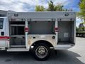 A 2009 Ford F-550 with an open utility box featuring two side compartments and a metal exterior with diamond plating