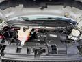 Engine compartment of a 2020 Chevrolet Express showing various mechanical components and parts including hoses coolant reservoir and air intake system