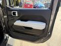 A 2021 Jeep Gladiator door panel featuring a black interior with a white armrest and a door handle