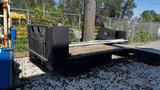 A black 2000 Service Flat Deck 8 Foot with a wooden surface and metal frame resting on gravel in an outdoor area