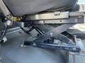 Mechanism of an adjustable seat in a 2007 Freightliner M2 106 showing a black metal frame with a scissor lift design and a cushion resting on top