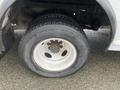 A close-up view of a flat tire on a 2012 Ford Econoline with a worn rim and tread showing signs of deterioration