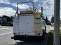 A white 2008 Ford F-550 with a large yellow ladder rack on top and a distinctive rear storage compartment