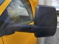 Close-up of the side mirror of a 2017 GMC Savana with a yellow exterior and partial reflection visible in the mirror glass