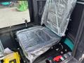 A 2024 AGT Industrial Green QH13R Mini Excavator seat covered in plastic with controls visible nearby