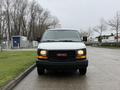A 2014 GMC Savana van is parked, featuring a white exterior and a black grille with a red GMC logo