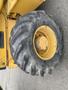 A close-up of a large yellow tire from a 2012 John Deere 310SJ with a rugged tread pattern and slight wear on the rubber surface