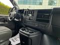 Interior of a 2023 GMC Savana showing the steering wheel dashboard and console with storage compartments and controls