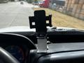 A dashboard mounted phone holder with a support bracket attached to a white dashboard of a 2006 Hino 268 truck