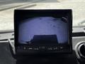 A dashboard display showing a rearview camera image with a view of the ground and some objects in the distance