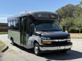 A 2019 Chevrolet Express bus with a silver and black exterior featuring large windows and a raised front area for passengers