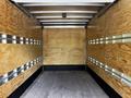 A 2018 Isuzu NPR with an empty cargo area featuring plywood walls and metal strips for securing loads