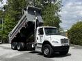 A white 2010 Freightliner M2 106 dump truck with a raised bed displaying a silver body and orange lights on the cab