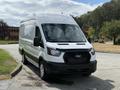 2021 Ford Transit van with a white exterior and black grille parked at an angle on a concrete surface
