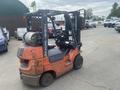 A 2010 Toyota 7FGGU25 forklift with an orange body and black forklift attachment visible from the side