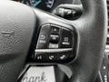 Close-up of a steering wheel control panel from a 2023 Ford Transit featuring buttons for navigation and audio controls