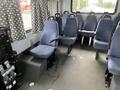 Interior of a 2012 Chevrolet Express showing several blue upholstered seats and a control panel on the side with a black seat for the driver