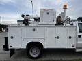 A 2016 Ford F-550 with a utility truck bed equipped with multiple compartments and a mounted aerial lift on top