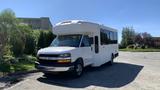 A white 2011 Chevrolet Express bus with a large front and tinted windows parked on a paved surface