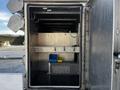 An empty compartment of a 2011 Ford F-450 SD with metal walls and a shelf inside featuring a blue and yellow container