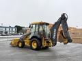A 2011 John Deere 310SJ 4x4 Wheel Loader with an extended hoe and a 4 in 1 bucket is positioned at an angle showcasing its hydraulic arm and rear digging mechanism