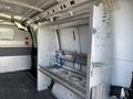 A metal shelving unit fixed inside the cargo area of a 2014 Chevrolet Express van with blue straps securing it in place