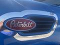 A blue 2008 Peterbilt 340 truck with a prominent red and silver logo featuring the word Peterbilt in cursive script