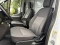 Two gray fabric seats in a 2023 Ford Transit van's cab with a steering wheel and dashboard partially visible