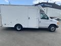A white 2004 Ford Econoline box truck with a side door and rounded roof design parked on a flat surface