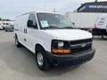 A white 2013 Chevrolet Express van with a black front grille and chrome wheels parked on a lot