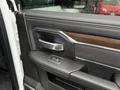 A close-up view of the door handle and interior armrest of a 2024 RAM 5500 featuring a sleek black design with wood accents and a control button