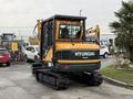 2022 Hyundai R55-9A compact excavator with a yellow and black exterior equipped with a cab and tracks visible in the foreground