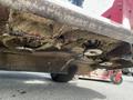 A 2014 Toro Groundmaster 5910 mower underside showing accumulated grass clippings around the blades and deck with visible wheels and components