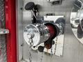 A chrome fire hydrant nozzle attached to a red hose with a chain securing it in place visible on a metallic panel
