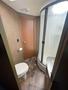 Interior view of a bathroom featuring a toilet a curved shower stall and a small sink with a counter