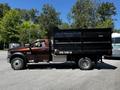 A 2015 RAM 5500 dump truck with a black cargo bed and shiny wheels parked on a pavement